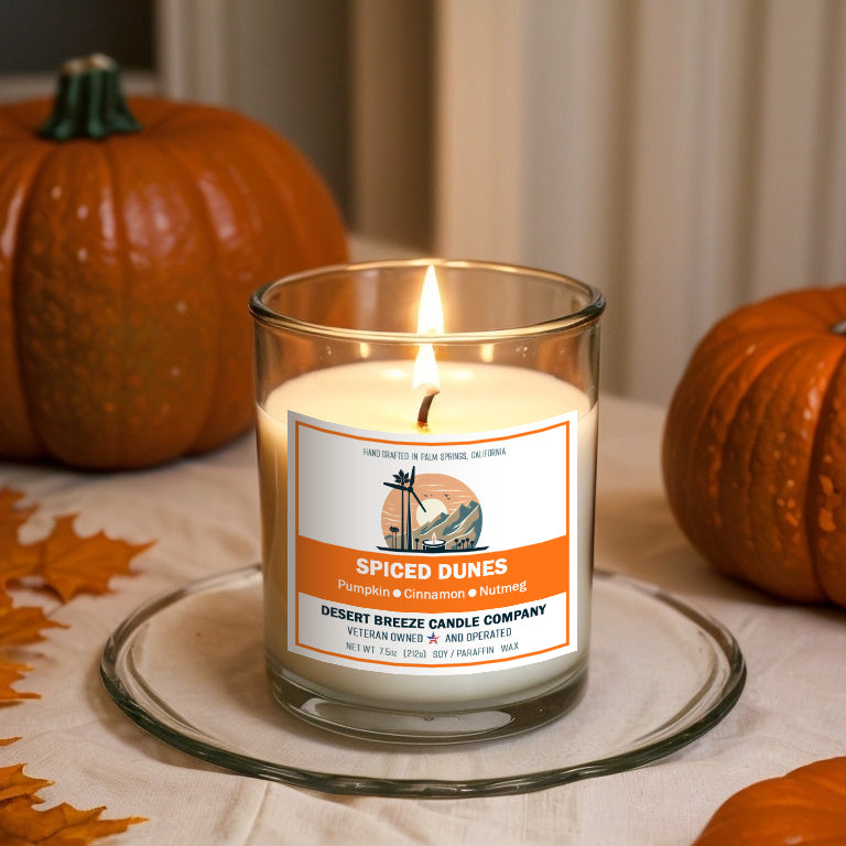 white candle in clear tumbler on table with pumpkins