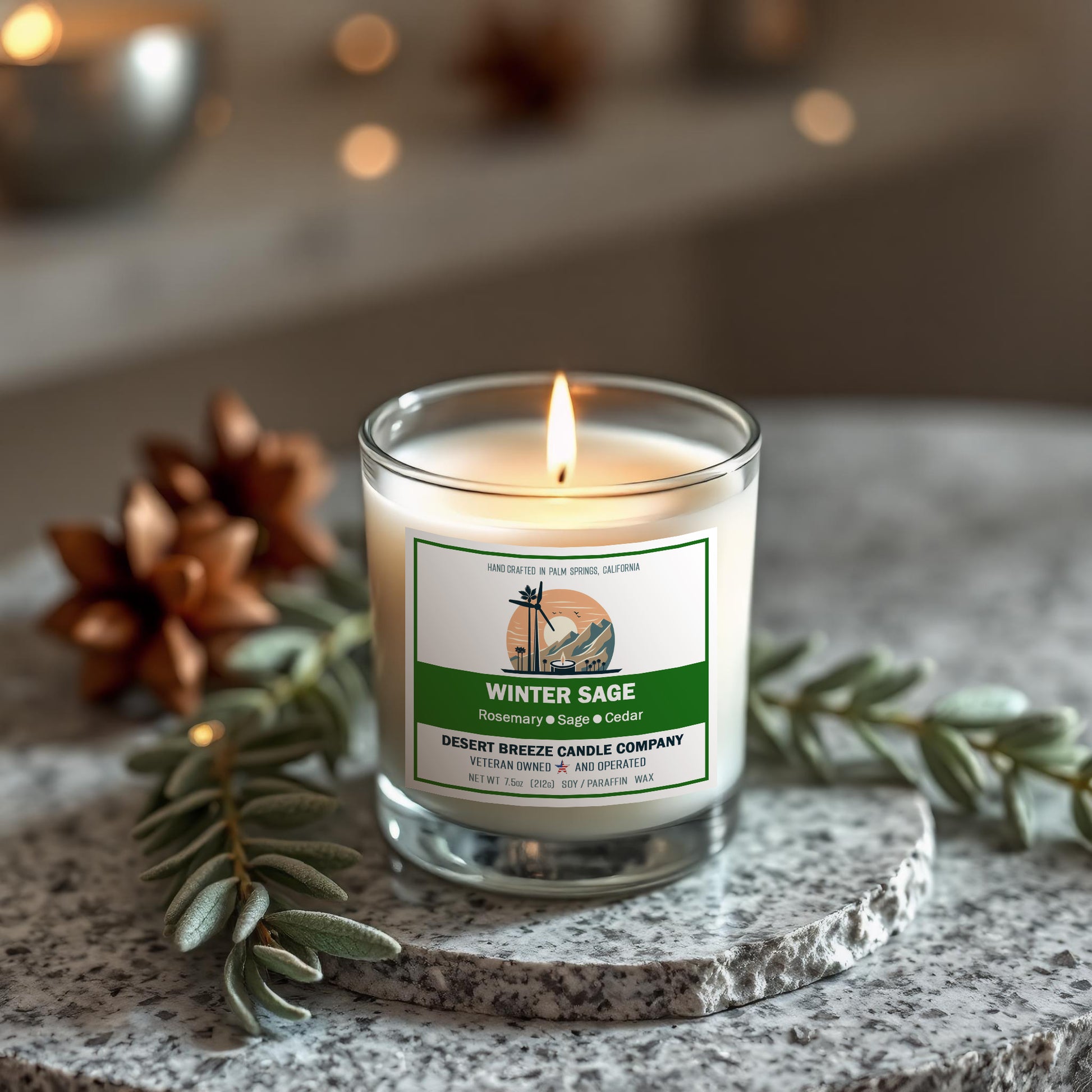 White candle in clear tumbler on granit table with sage and pine cones.