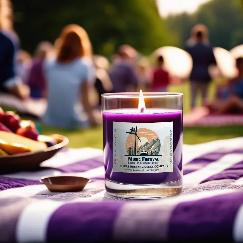 A purple candle in clear tumbler on a picnic blanket at a music festival